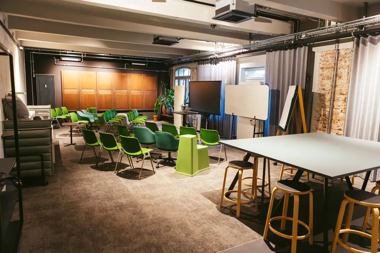 Atelier im club199 mit Stuhlkreis, Hochtischen und Sichtziegelwand