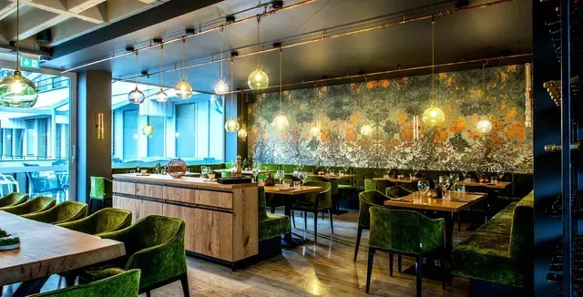 Restaurant im KORN'S mit grünen Sesseln und Kunstwand